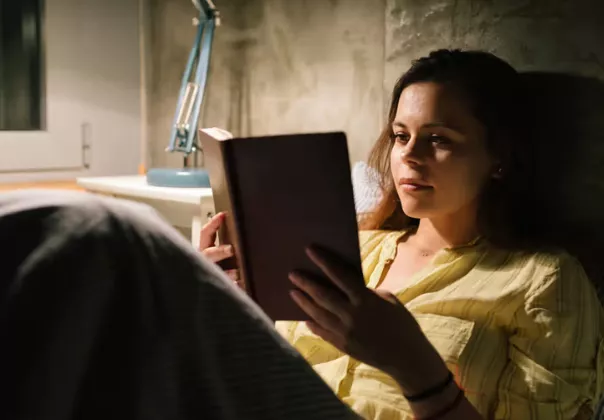 Woman reading in bed with a lamp on